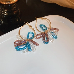 Détail de créoles dorées avec perles de cristal colorées sur un plateau en céramique