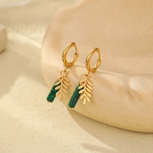 Detailed close-up of gold leaf earrings with green malachite stone on soft background