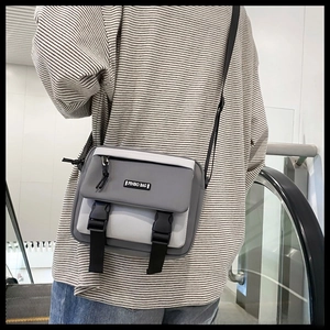 Detail of grey and beige crossbody bag with adjustable strap and buckle closure