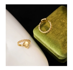 Dettaglio anello dorato con trama a intreccio e base a forma di cuore sul retro