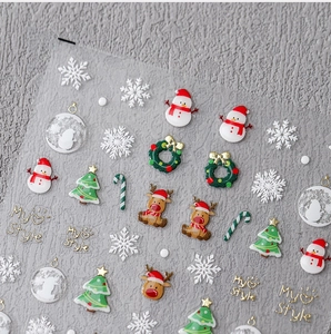 Macro shot of festive Christmas nail stickers with snowmen, reindeer, and golden glitter details