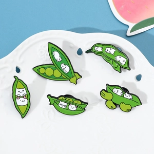 Set of five enamel pins featuring cute cats in green pea pods displayed on a white tray