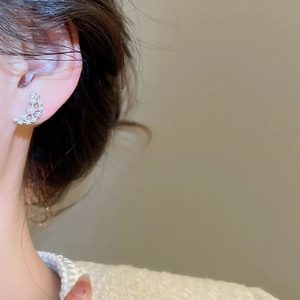 Close-up of crescent moon earring with pearls and shimmering zircons on model ear
