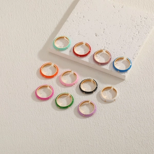 Close-up of colorful enamel and gold-plated earrings set on a beige textured stone base