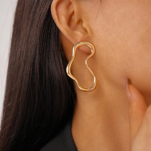 Close-up of golden irregular wave earrings on model showcasing metallic luster