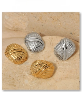 Detail of gold and silver vintage striped button earrings on beige stone backdrop