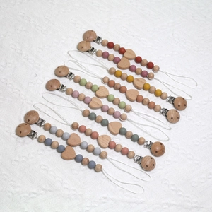 Set of 8 silicone and beech wood pacifier clips with heart charms on white fabric
