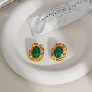 Detail of vintage gold-plated titanium earrings with oval green natural stone insets