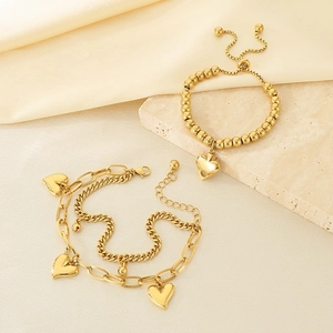 18K gold plated titanium heart bracelets on textured stone and silk background