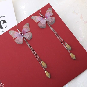 Détail de boucles d'oreilles papillon coréennes avec ailes en tissu violet et pompon