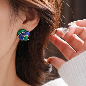 Detail of vintage enamel leaf earrings in blue and green on a female model