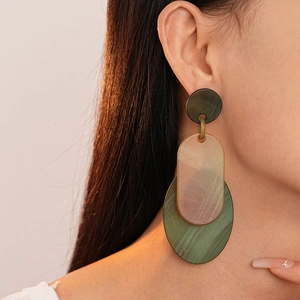 Gros plan de boucles d'oreilles en acrylique avec effet marbré ambre et vert émeraude