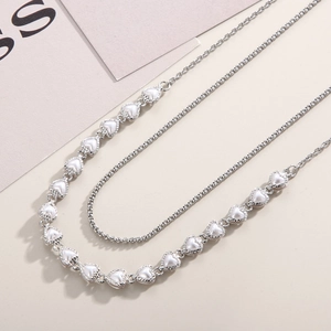 Detail of silver double-layered heart necklace with elegant white pearlescent inlay