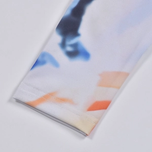 Close-up of white sleeve with blue and orange tie-dye print and precise stitching