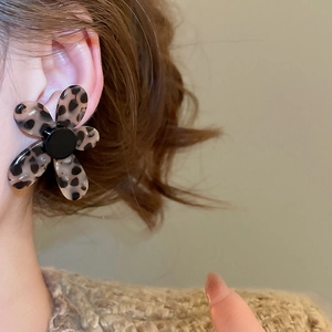 Close-up of a floral leopard print earring worn by a model in a warm setting