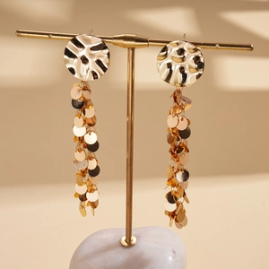 Detailed view of gold multi-layered sequin tassel earrings with textured round studs