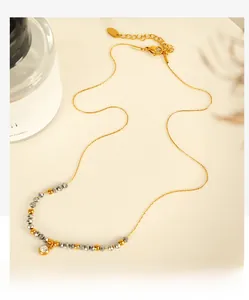 Detail view of gold necklace with grey faceted beads and sparkling zircon pendant