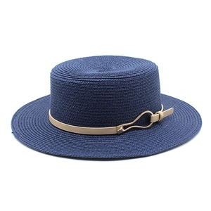 Detail of navy blue straw boater hat with khaki leather strap and gold buckle