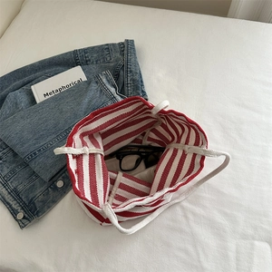 Striped canvas tote bag with thick rope handles shown in a lifestyle flat lay setting