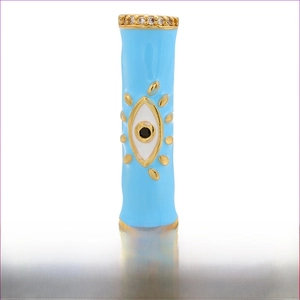 Dettaglio macro del tubo in ottone placcato oro 18K con occhio smaltato blu e zirconi