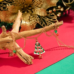 Detailed view of golden Christmas tree pendant with red and green beads on a wooden branch