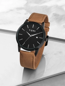 Detailed close-up of TOMI watch showing matte black dial with date window and brown suede strap
