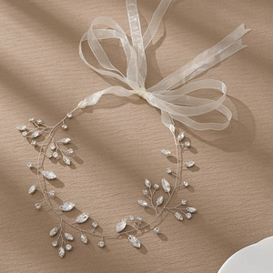 Silver bridal hair vine with crystal leaves and white ribbons on a textured background