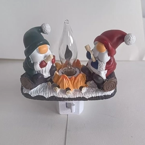 Close-up of resin Santa Claus gnomes decor with warm glowing light bulb on white base