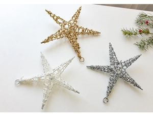 Close-up of sparkling Christmas star ornaments in gold, silver, and white with glitter coating