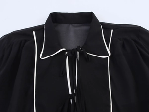 Détail du col polo contrasté avec liseré blanc et nœud papillon sur robe noire