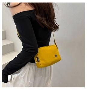 Dettaglio della borsa a tracolla in nylon giallo impermeabile indossata da una modella casual