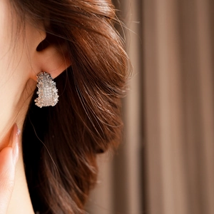 Gros plan de boucles d'oreilles courbes en argent avec zircons scintillants sur mannequin