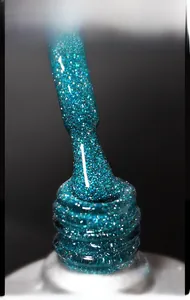Macro shot of peacock blue glitter nail gel polish texture with silver sparkles