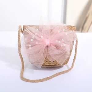 Detail einer handgewebten Strohtasche mit rosa Tüllschleife und Perlenverzierung