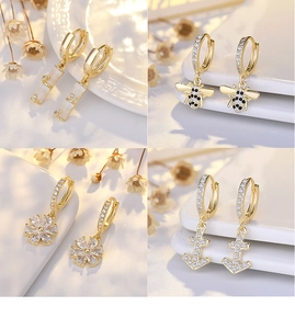 Detail of four gold hoop earrings featuring bee, flower, bamboo, and anchor designs