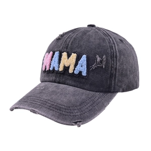 Macro detail of rainbow MAMA embroidery on washed charcoal denim distressed baseball cap