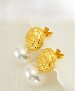 Macro shot of French vintage pearl stud earrings with textured gold metal detail