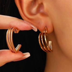 Détail de grandes boucles d'oreilles cœur dorées à trois couches portées à l'oreille