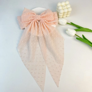 Macro detail of peach Swiss dot mesh fabric and long ribbon on a large bow hair clip