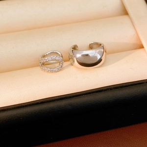 Macro view of silver U-shaped zircon ear cuffs and polished wide band earrings