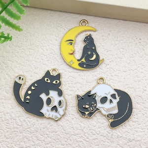 Macro shot of three dark gothic enamel cat charms with skull and moon details