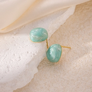 Elegant mint green marble texture titanium steel earrings on a white stone background