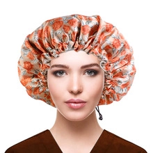 Close-up of orange floral satin sleep cap with adjustable drawstring and elastic band