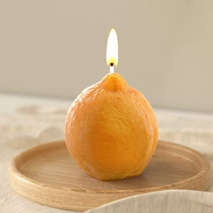 Detailansicht einer orangen Zitronenkerze mit realistischer Textur und warmer Flamme