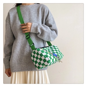 Detail of green checkerboard Boston bag with wide canvas strap worn by a model