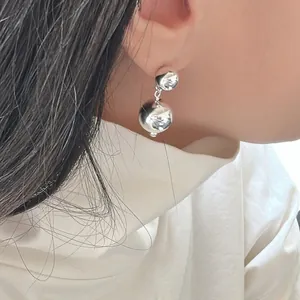 Primo piano macro di un orecchino minimalista in argento a doppia sfera indossato da una modella