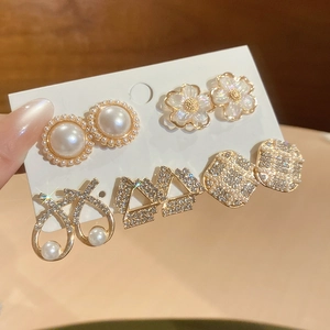 Close-up of elegant gold earrings set with pearls and crystals on a display card