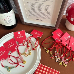 Handwoven red rope bracelet featuring golden horse charm and colorful beads on a gift card