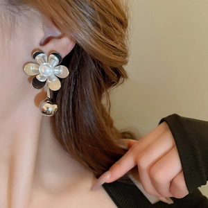 Close-up of model wearing black and white flower earrings with pearl and silver bead