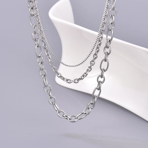 Three-layer silver stainless steel necklace with curb and cable chains on white stand